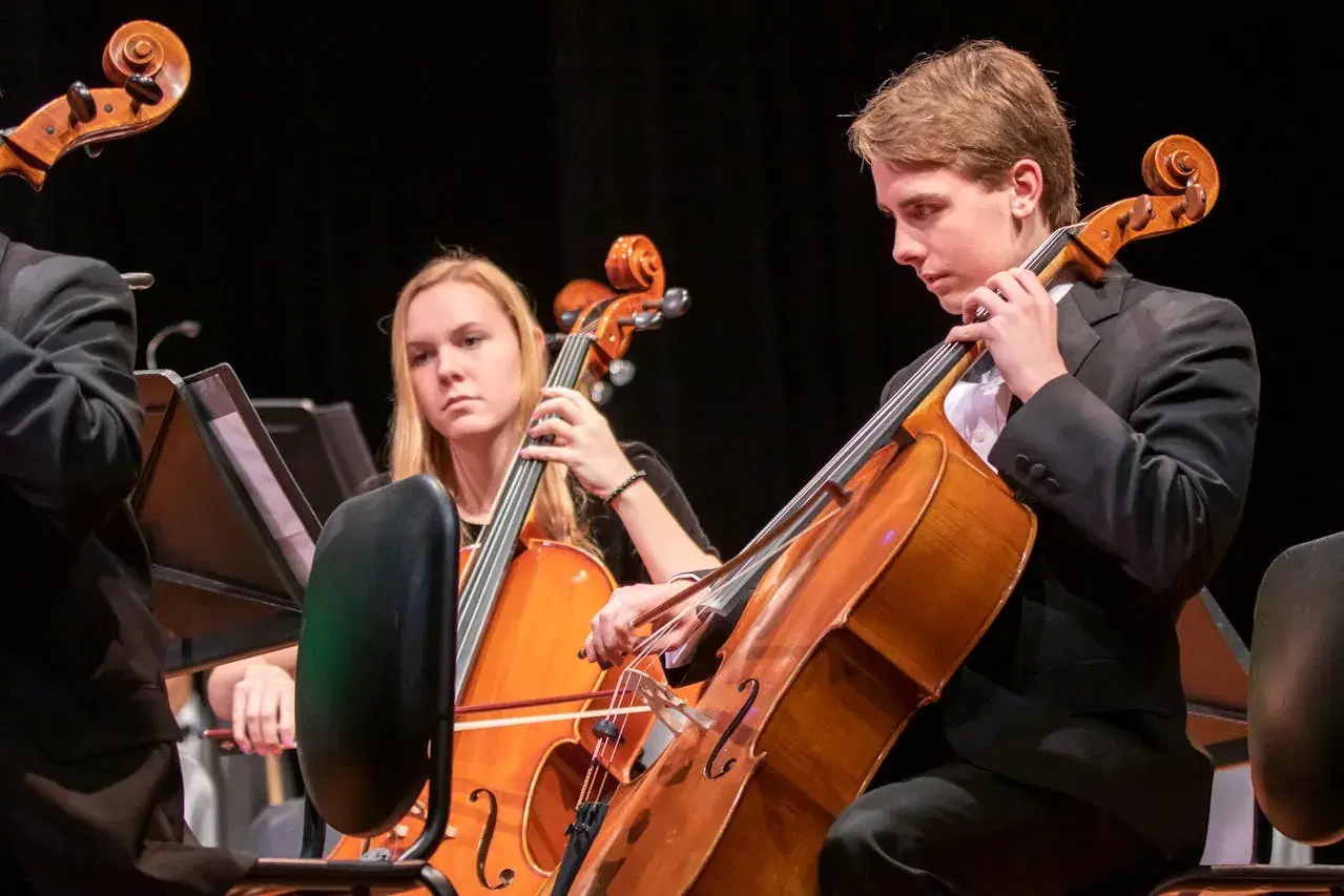 School music program students practicing instruments with music director in educational setting